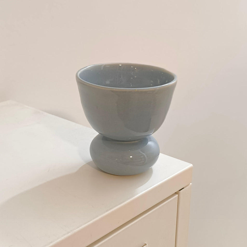 A light blue ceramic pedestal cup with a glossy finish