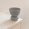 A light blue ceramic pedestal cup with a glossy finish