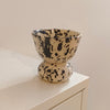 A ceramic pedestal cup with a black speckled pattern